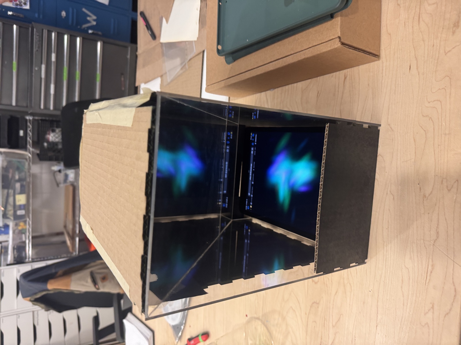 Cardboard prototype of the Pepper's Ghost display box with an aurora projection visible inside